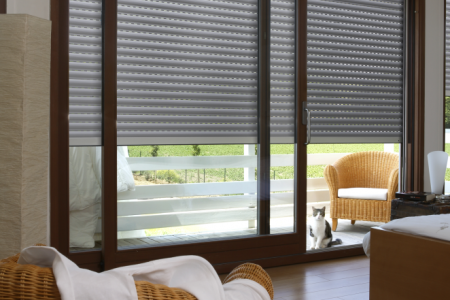 Volet roulant en aluminium gris installé devant une grande baie vitrée.