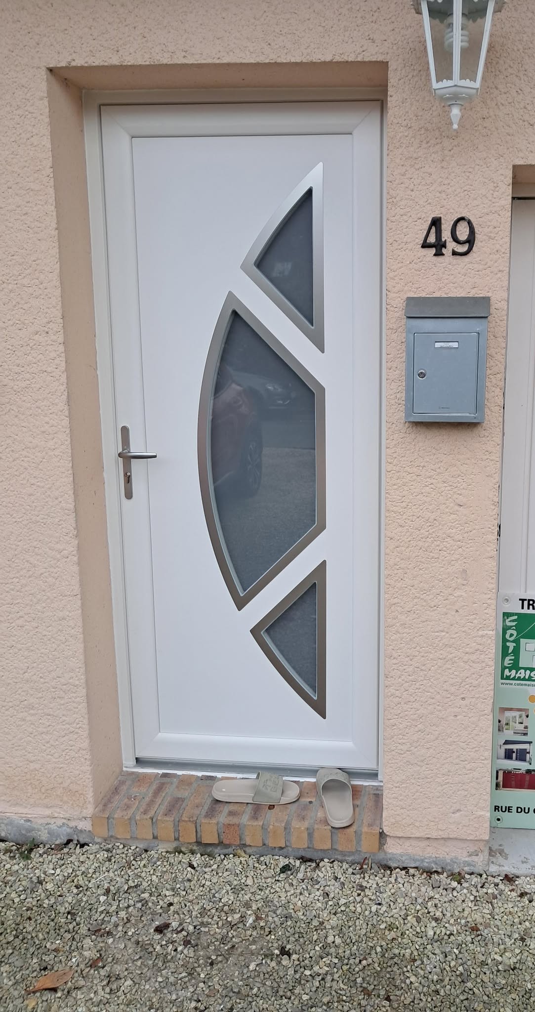 Porte d'entrée en PVC blanc avec verre décoratif et poignée en métal.