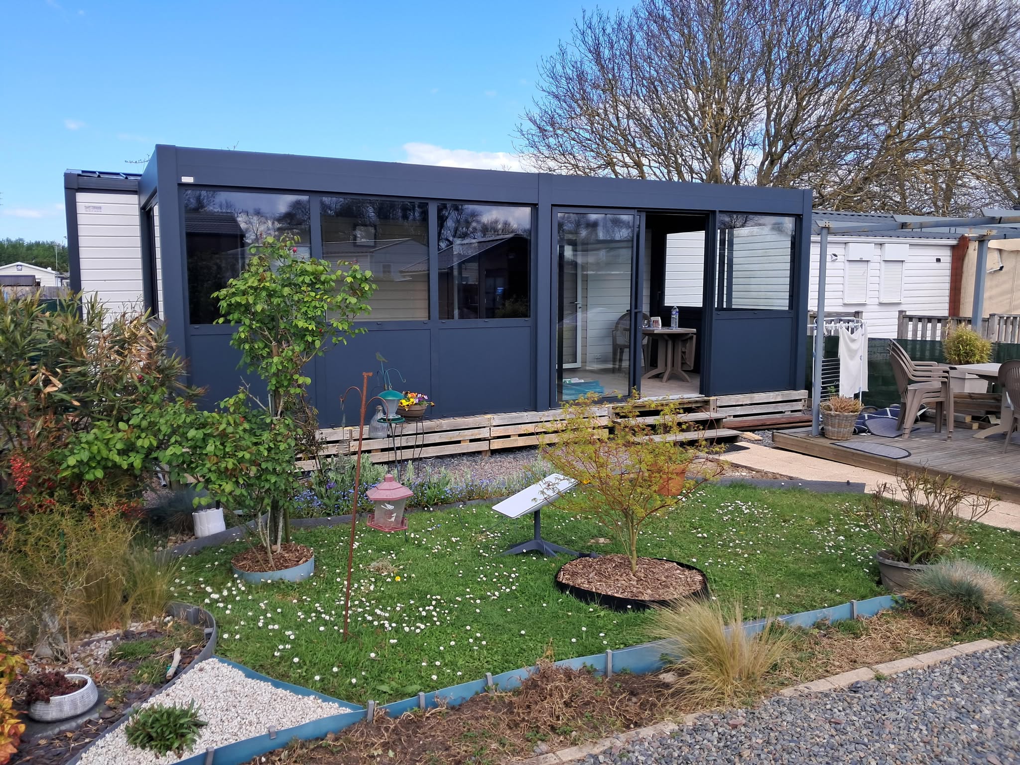 Véranda en PVC avec grandes fenêtres et structure en aluminium, conçue pour un usage extérieur.