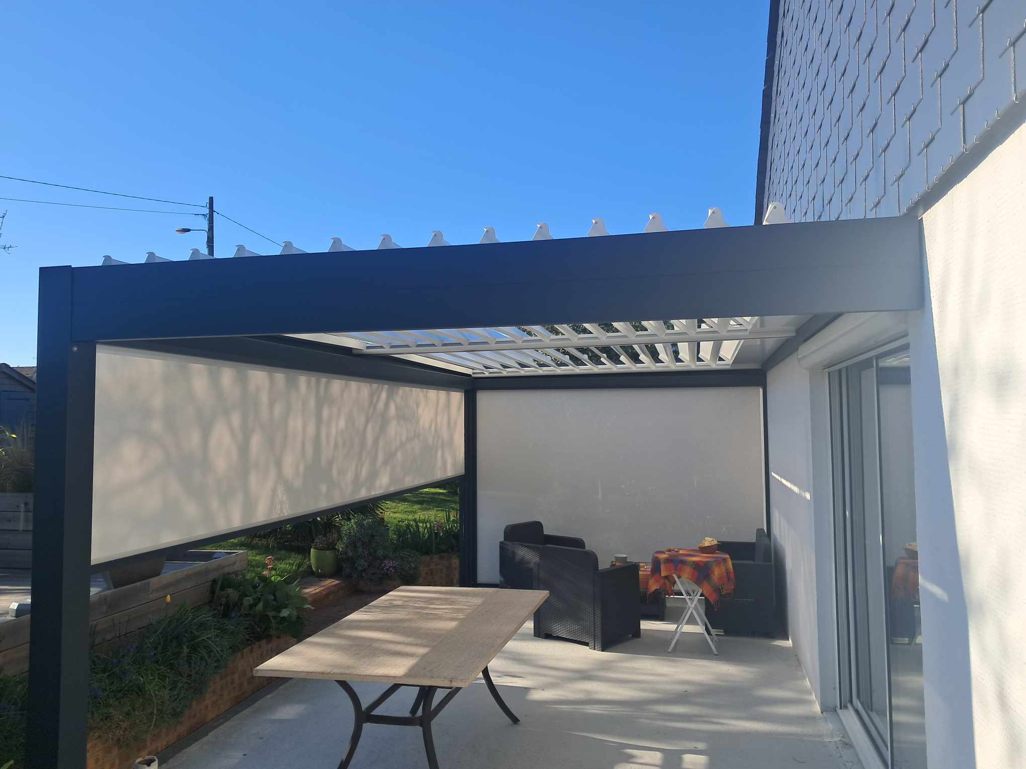 Pergola en aluminium avec toiture rétractable et parois en toile.