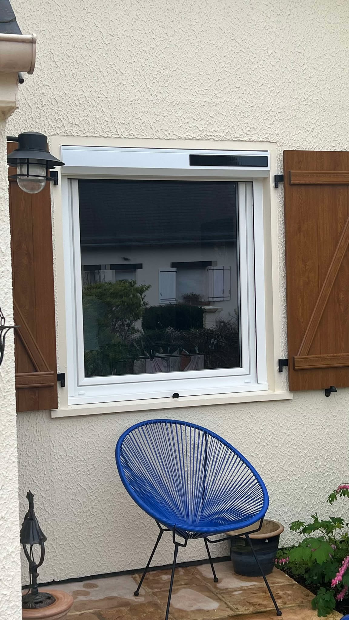 Fenêtre en PVC blanche avec volets en bois brun.