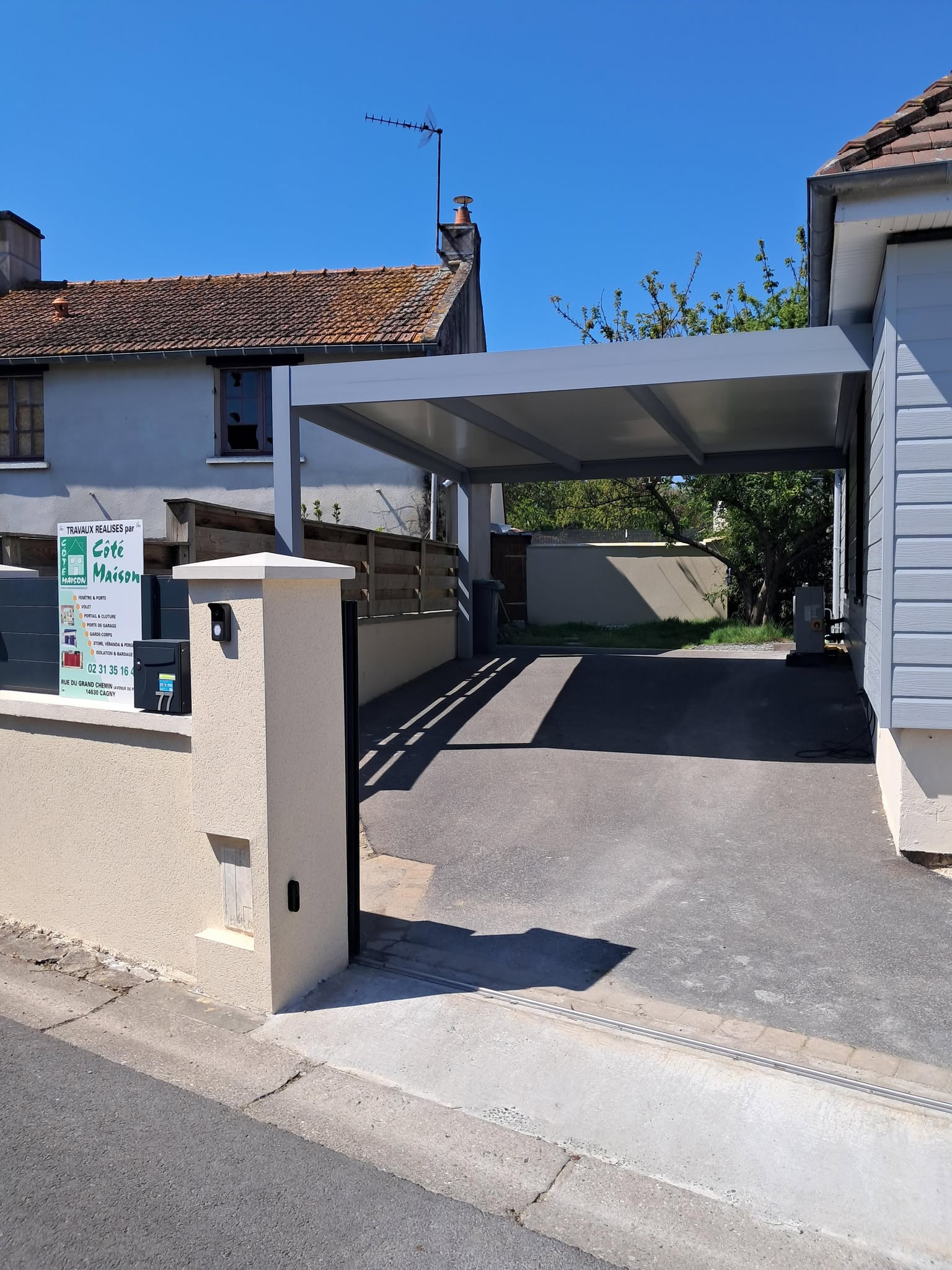 Carport en métal gris avec structure réalisée pour abriter un véhicule.