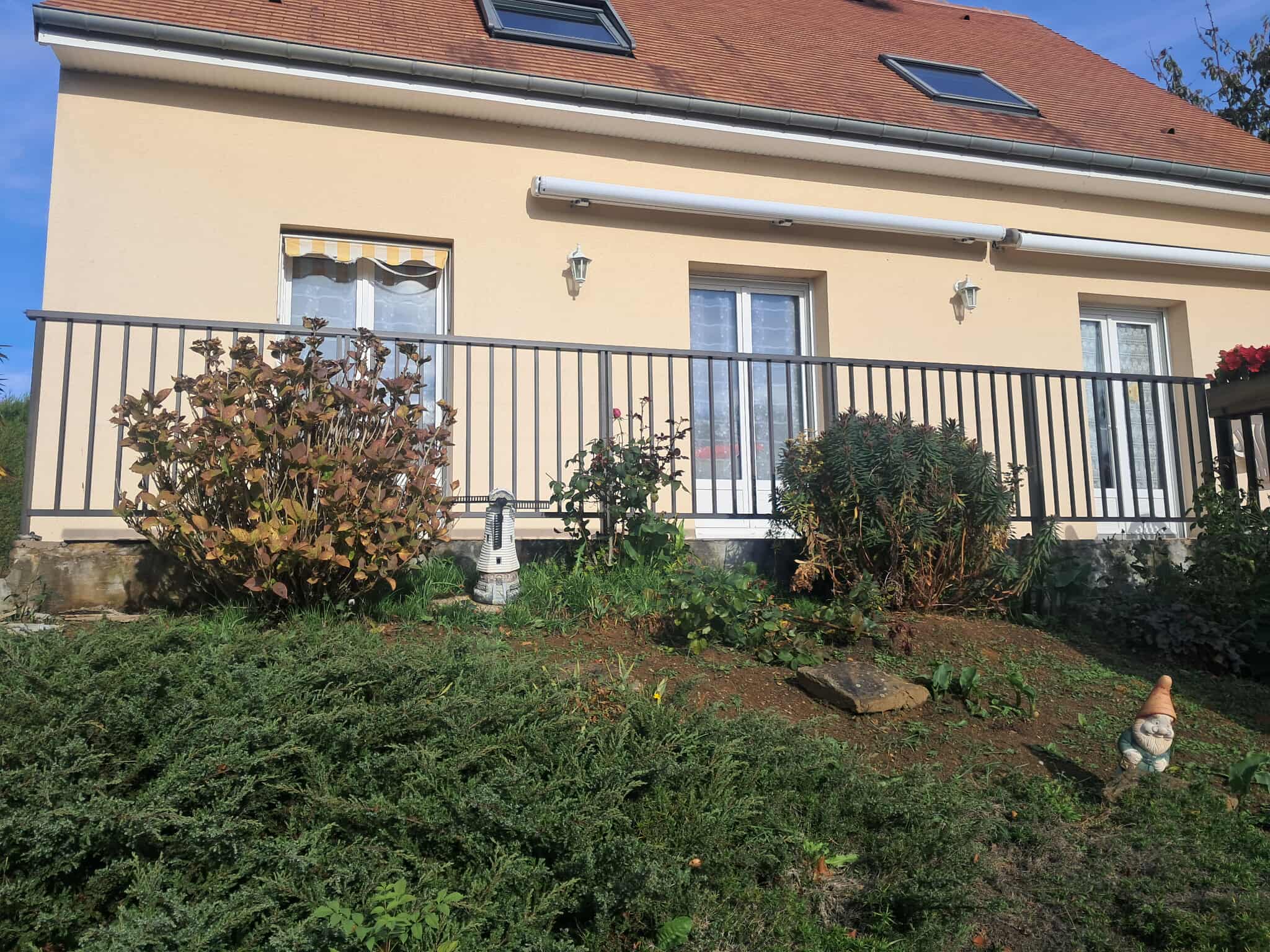 Barrière en métal avec garde-corps noir, installée devant une maison.