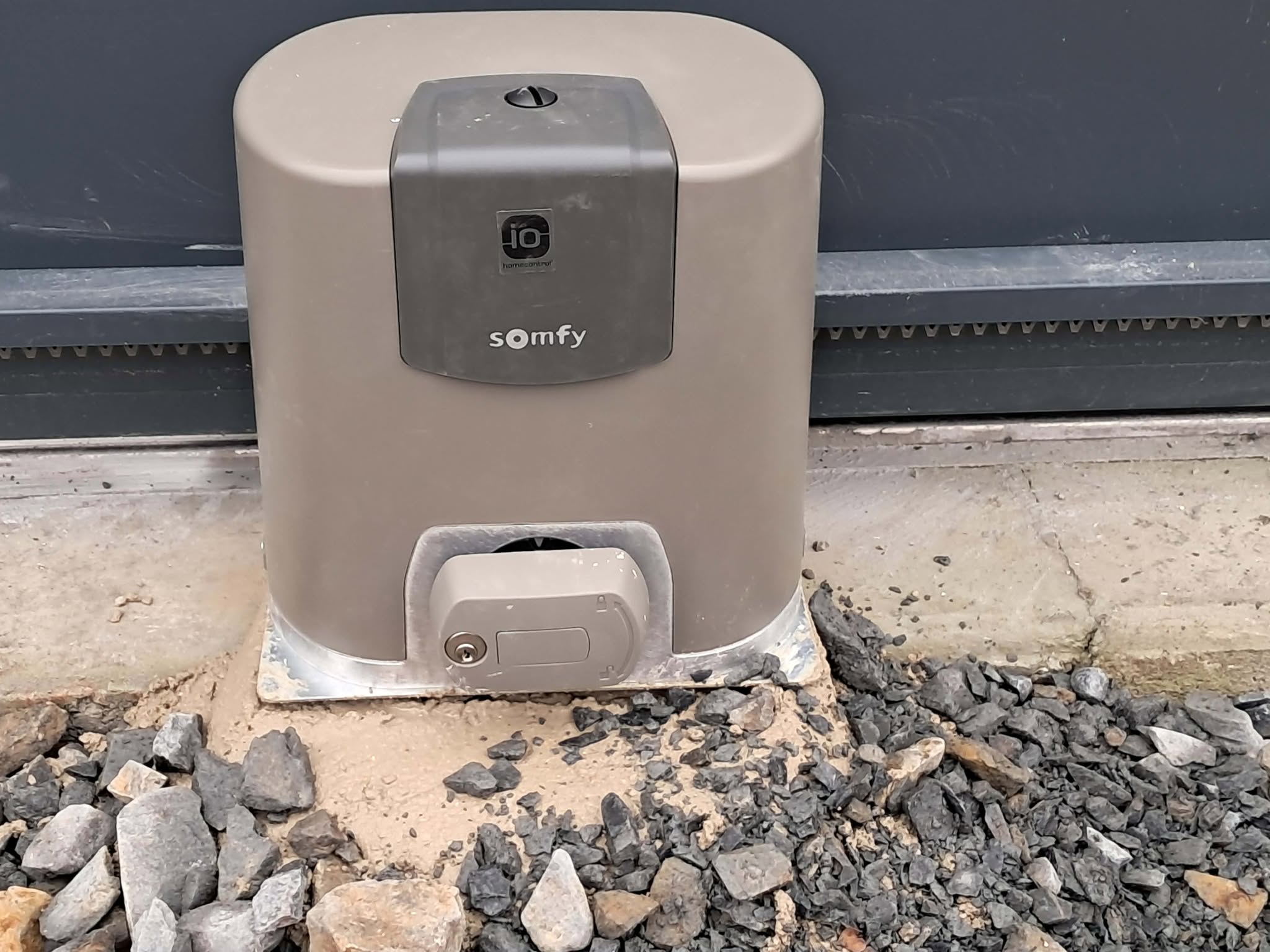 Moteur de portail Somfy, couleur grise, installé sur une base en béton.