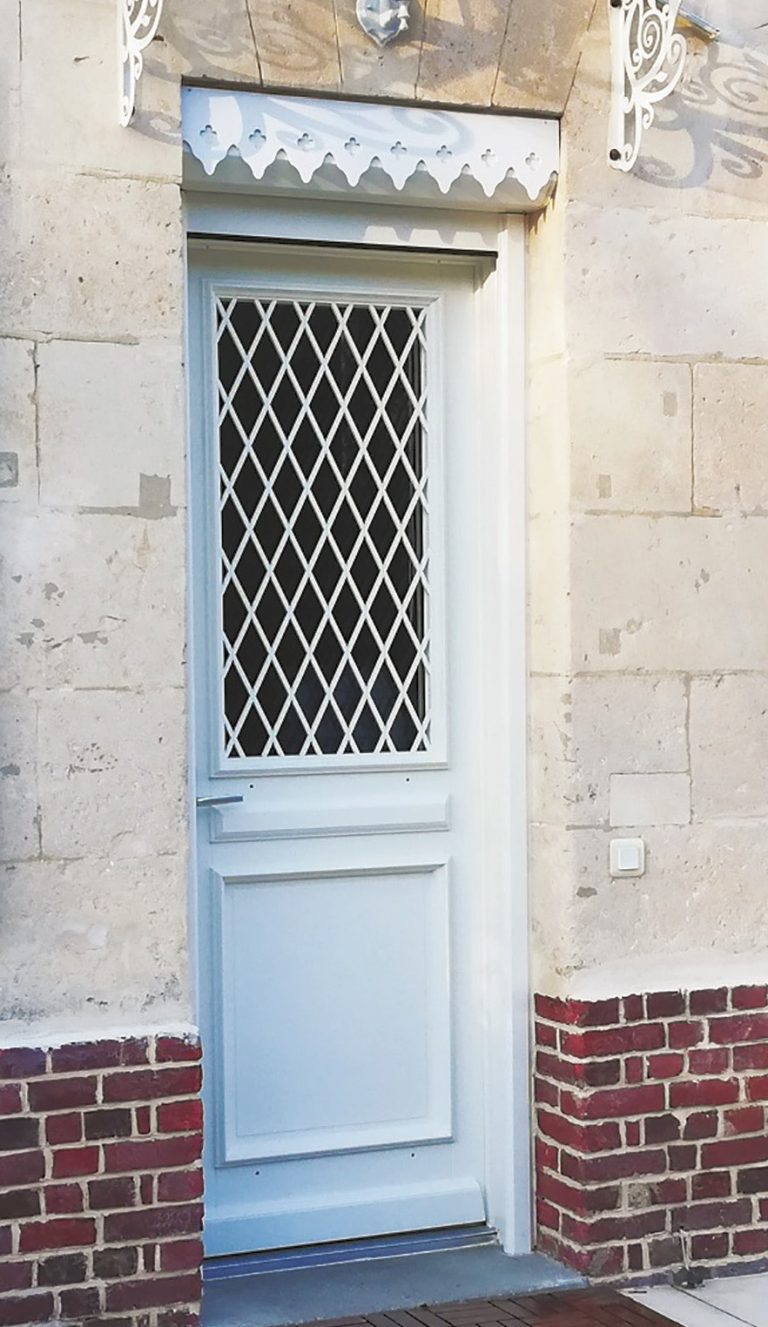 Porte en bois blanc avec grille de sécurité en métal.