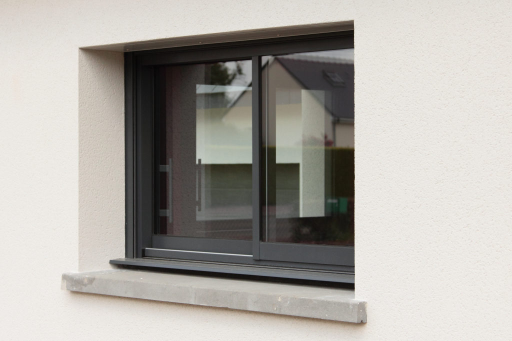Fenêtre en PVC noir à ouverture coulissante, avec cadre et vitrage isolant.