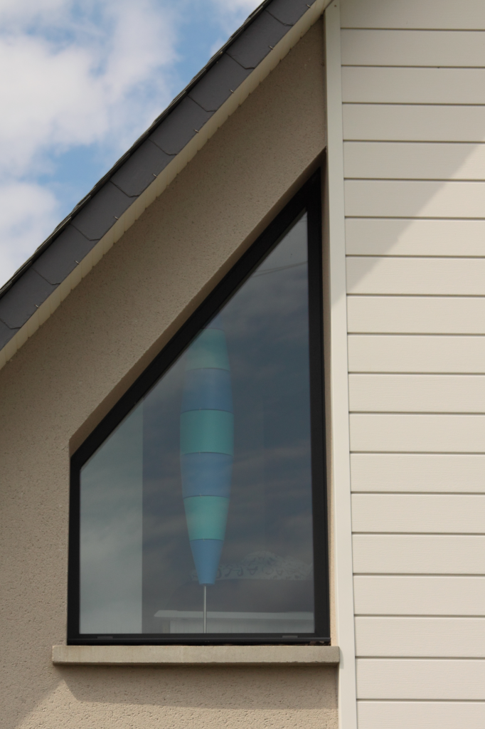 Fenêtre en angle avec chassis noir, verre transparent et cadre en matériau composite.