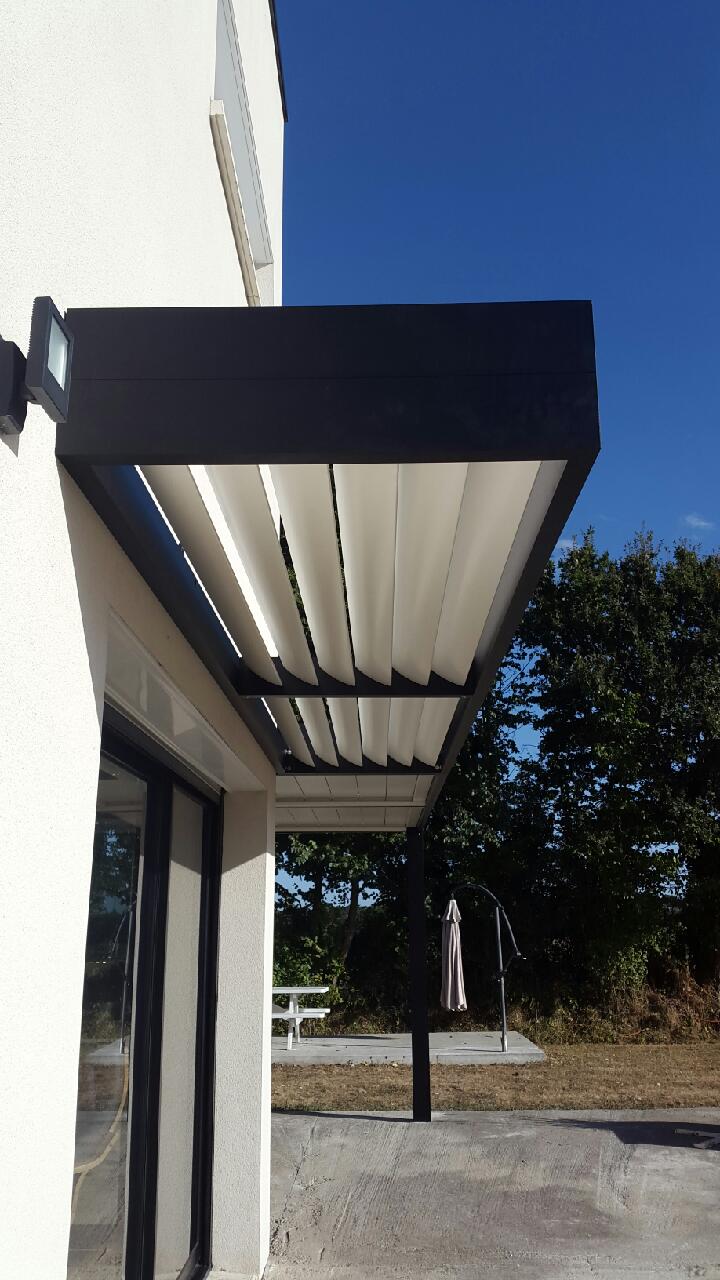 Pergola en aluminium noir avec lames orientables, installée sur la terrasse d'une maison.
