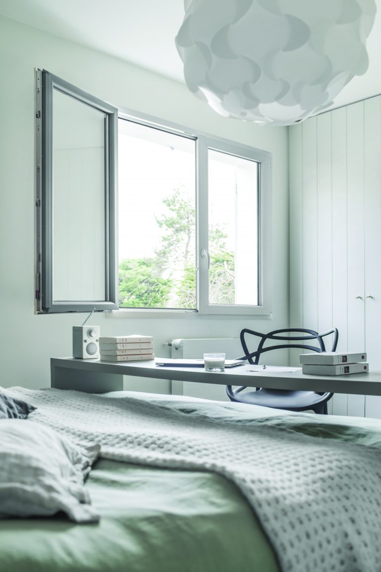 Fenêtre mixte PVC/aluminium ouverte avec cadre gris et vitrage, installée dans une pièce moderne.