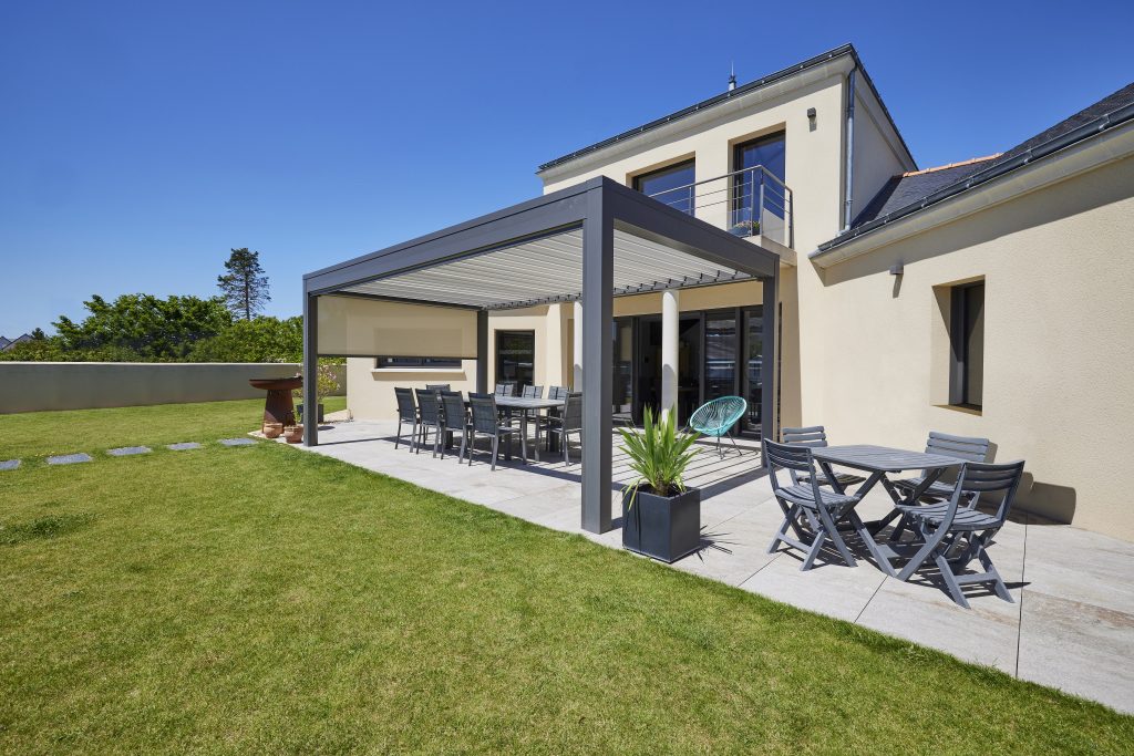 Pergola en aluminium grise, avec une structure à lames orientables. Mobilier de jardin en aluminium et bois.