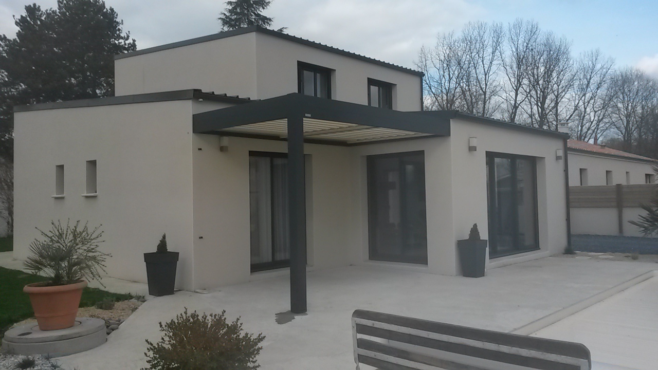 Pergola en aluminium gris installée sur une maison moderne avec grandes baies vitrées, le tout sur une terrasse en béton.