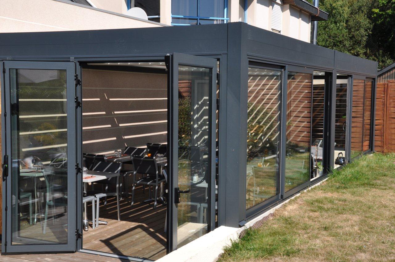 Véranda en aluminium avec grandes baies vitrées et porte coulissante.