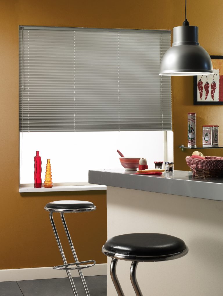 Store plissé en aluminium gris installé sur une fenêtre.