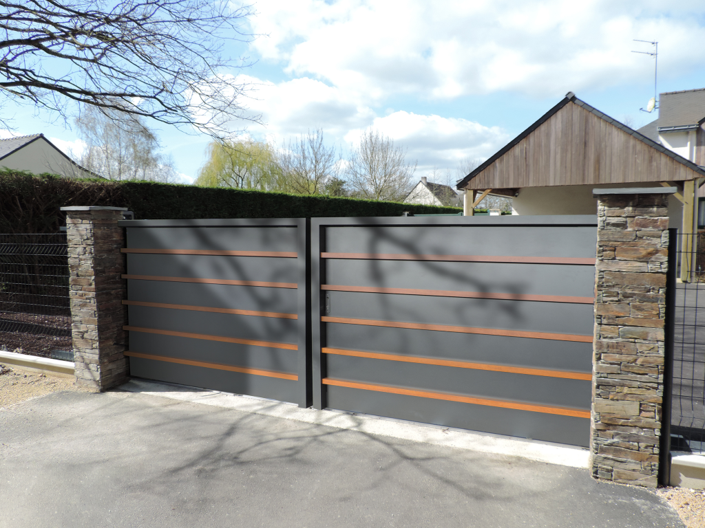 Portail en aluminium gris avec lames en bois, monté sur piliers en pierre.