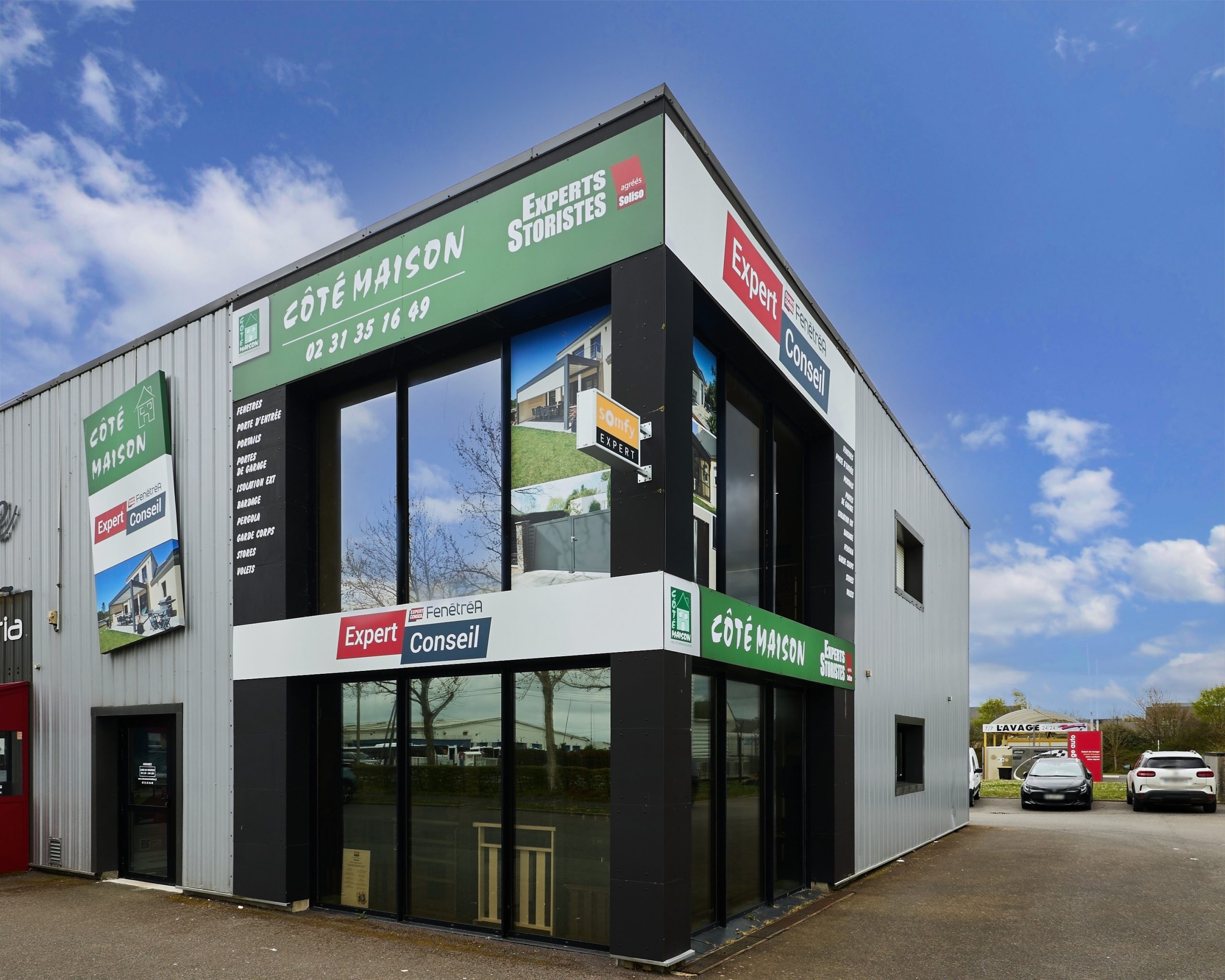 Façade de bâtiment avec vitrages en verre et panneaux en aluminium. Enseignes commerciales visibles.