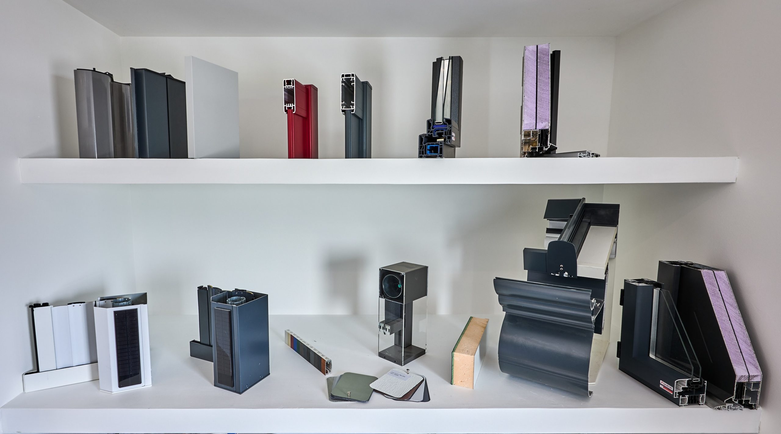 Échantillons de profilés en aluminium pour fenêtres et porte-fenêtres, avec diverses finitions et isolations.