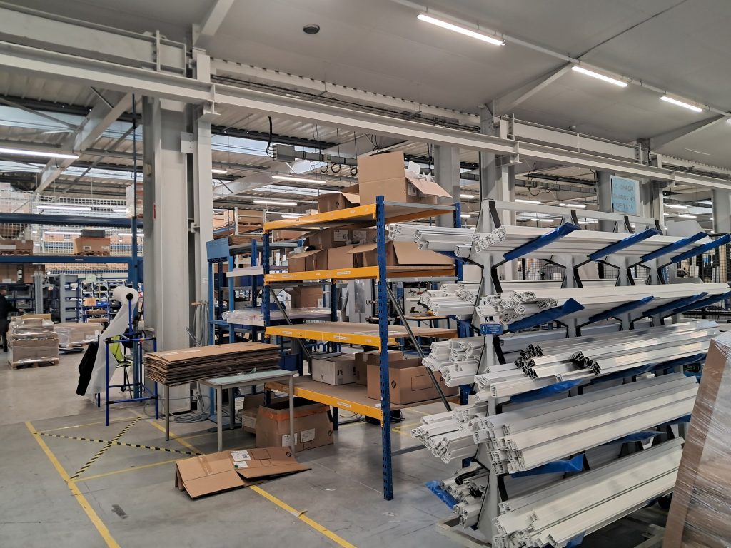 Étagères avec profilés en aluminium pour fenêtres et portes, ainsi que panneaux de bois empilés.